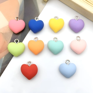 Close-up of ten colorful resin heart charms with silver metal rings for DIY jewelry making