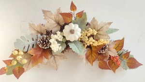 Detail of autumn garland with white pumpkin, maple leaves, pine cones and berries