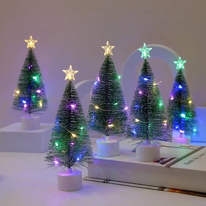 Close-up of mini glowing Christmas trees with colorful LED lights and star toppers