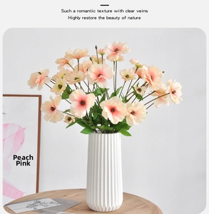 Peach pink artificial silk poppy bouquet in a white textured ceramic vase on a wood table