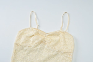 Close-up of beige floral lace camisole with thin straps and ruffled chest detail