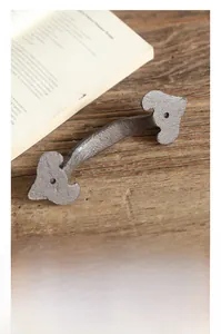 Retro cast iron door handle with heart shaped ends on vintage wood background