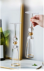 Detail of two crystal champagne glasses with gold rims and stems holding bubbly wine