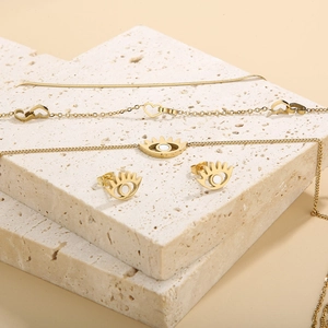 Golden stainless steel set with heart chains and evil eye stud earrings on stone