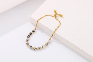 Adjustable gold beaded bracelet featuring natural dalmatian jasper stone beads with slider clasp