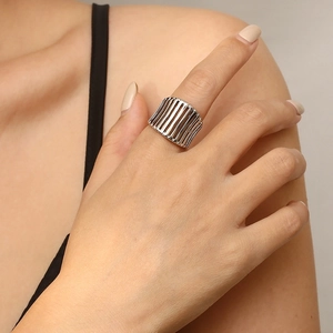 Detailed view of silver hollow wide band ring with vertical grid design on model hand