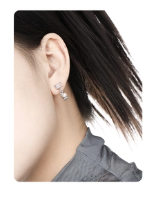 Detailed close-up of a silver earring with a square zircon and elegant white pearl pendant
