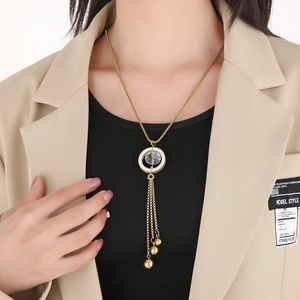 Detail of long gold tassel necklace with crystal sphere pendant on a blazer