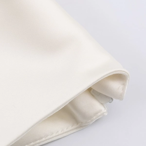 Detailed macro view of white satin fabric texture and premium stitched edge on the shirt