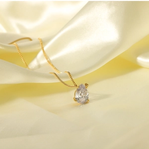 Detailed macro view of pear-cut white zircon pendant on gold-plated stainless steel chain
