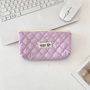 Close-up of a light purple quilted diamond-pattern pouch with zipper on a desk