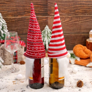 Knitted gnome Christmas wine bottle covers with red hats and white beards in snow scene