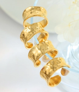 Detail of four hammered gold adjustable rings on a blue tube with white flowers