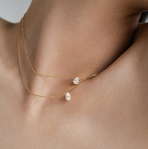 Close-up of double-layer gold chain necklace with oval clear gemstones on a model