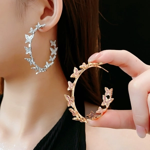 Gros plan de boucles d'oreilles papillon en forme de C, argentées et dorées, avec cristaux