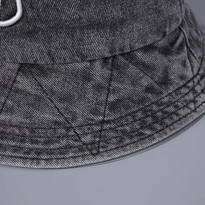 Gros plan sur les surpiqûres et la broderie blanche sur le chapeau bob en denim délavé