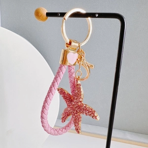 Detailed close-up of a pink rhinestone starfish keychain with woven leather rope strap