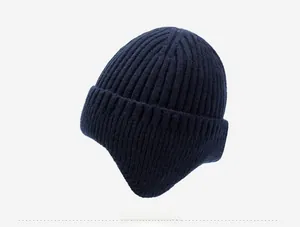Detail of dark blue knit winter hat featuring thick ribbed texture and silver metal button