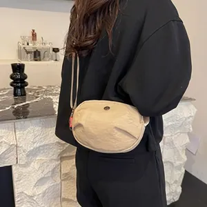 Detail view of the beige pleated crossbody bag showing its soft texture and compact size