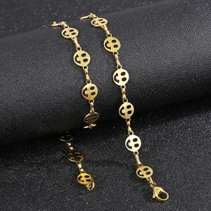 Detail of a golden titanium steel bracelet featuring linked cut-out smiley face charms