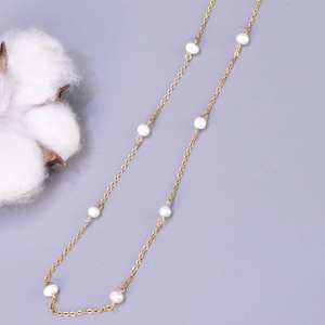 Detail of elegant gold chain necklace with natural freshwater pearls on soft background