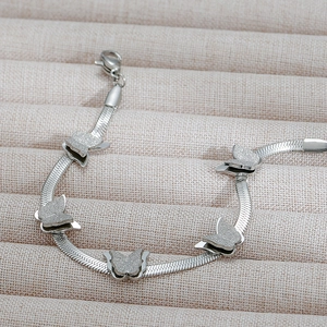 Macro view of silver butterfly charms on a stainless steel snake chain bracelet
