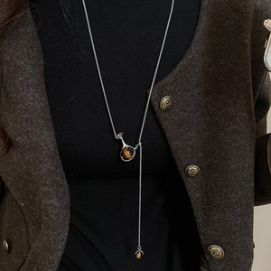 Detail of Y-shaped long necklace with tiger eye stone pendant on wool sweater