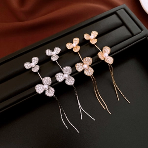 Détail de boucles d'oreilles fleurs avec pompons en argent et or, zircons et perles
