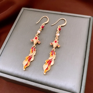 Detail of koi fish tassel earrings with red enamel work and small pearls on a jewelry box