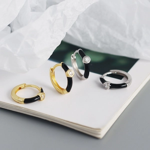 Macro shot of gold and silver hoop earrings with black enamel and tiny gemstones