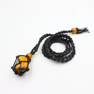 Detail of hand-woven black net holding a polished tiger eye stone with wooden beads
