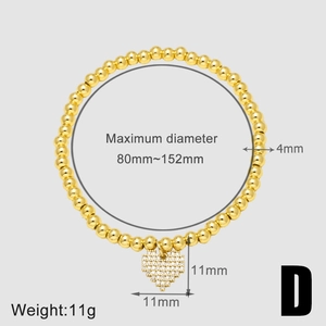 Dettaglio di un bracciale a sfere dorate con pendente a cuore impreziosito da zirconi
