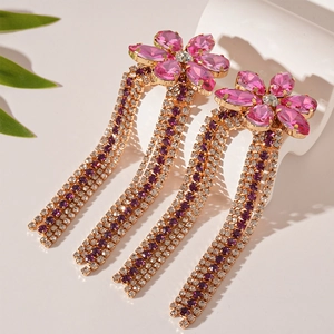 Elegant pink rhinestone flower earrings with long purple and white tassels on a white stand