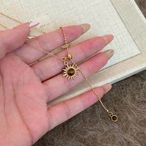 Detailed close-up of tiger eye stone sun pendant with mixed golden chain necklace