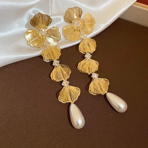 Detail of 18K gold plated flower earrings with crystals and pearl drops on silk