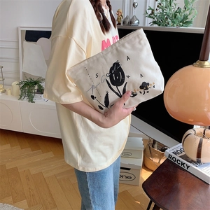 Close-up of cream canvas makeup bag with black floral embroidery and zipper detail