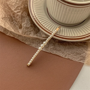 Detail shot of elegant gold hair clip with a row of gradient sized white round pearls