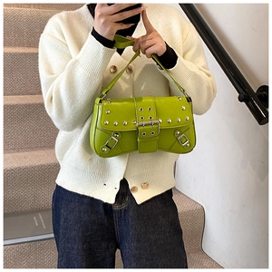 Detail of green punk shoulder bag with silver rivets and buckles in a lifestyle scene