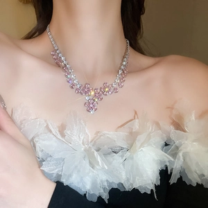 Primo piano della collana a fiori con cristalli rosa e bianchi indossata con pietre lucide
