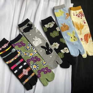 Flat lay of colorful Tabi socks with floral and bunny patterns on pleated fabric
