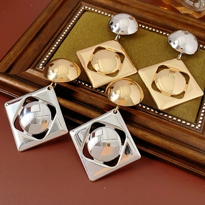 Detail view of silver and gold geometric drop earrings on elegant vintage leather background