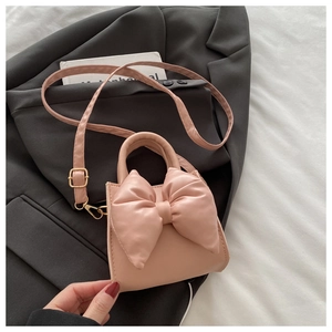 Close-up of pink fashion handbag with large bow detail and adjustable shoulder strap