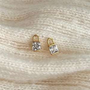 Minimalist gold padlock stud earrings with square clear zircon on white knit fabric