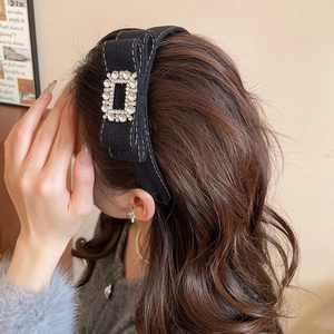 Detail of black flocked headband featuring a square rhinestone buckle and white stitching