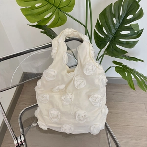 Detail of creamy white canvas tote bag with 3D fabric roses on a transparent chair