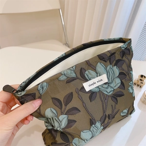 Detail view of jacquard floral makeup bag with simple wish label and smooth metal zipper