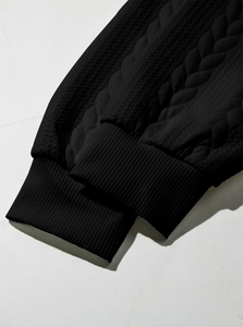 Detail shot of heavy-weight black cable knit sleeves with ribbed cuffs on winter sweatshirt