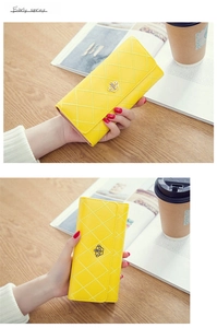 Detailed view of yellow quilted long wallet with a gold crown buckle in a lifestyle setting