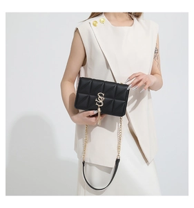 Close-up of black quilted leather bag with gold S-logo and metallic tassel detail