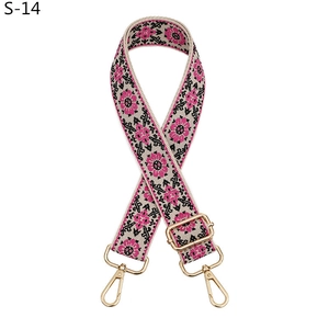 Detail of adjustable beige bag strap with pink floral embroidery and gold metal clips